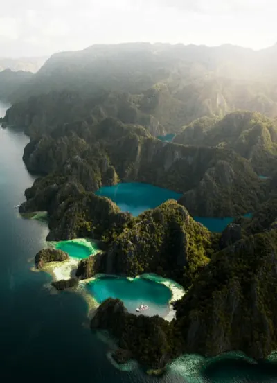 Turquoise lagoons enclosed by steep limestone cliffs, seen from the air