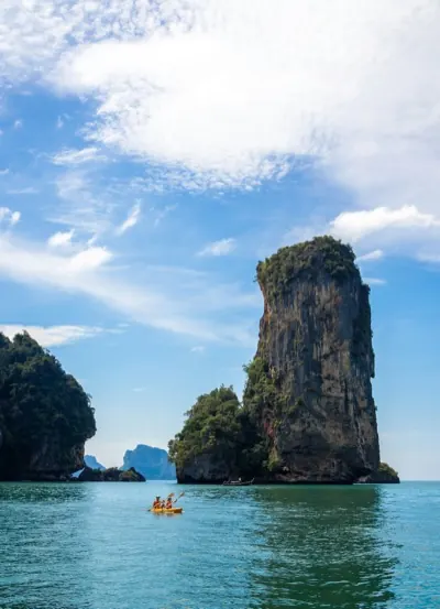 Kayakers beside a limestone island rising out of calm sea